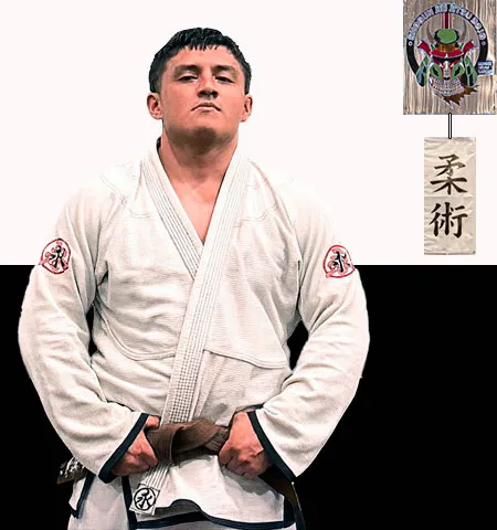Adal Becerril con gi blanco y cinta marrón de BJJ frente al muro del dojo Shogun Jiujitsu