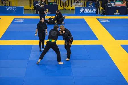 Combate entre cintas moradas en torneo de BJJ con supervisión femenina