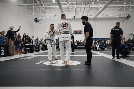 Competencia de jiu jitsu brasileño con gi blanco bajo supervisión oficial