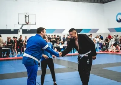 Competidores de BJJ con gi azul y negro se saludan antes de iniciar el combate.